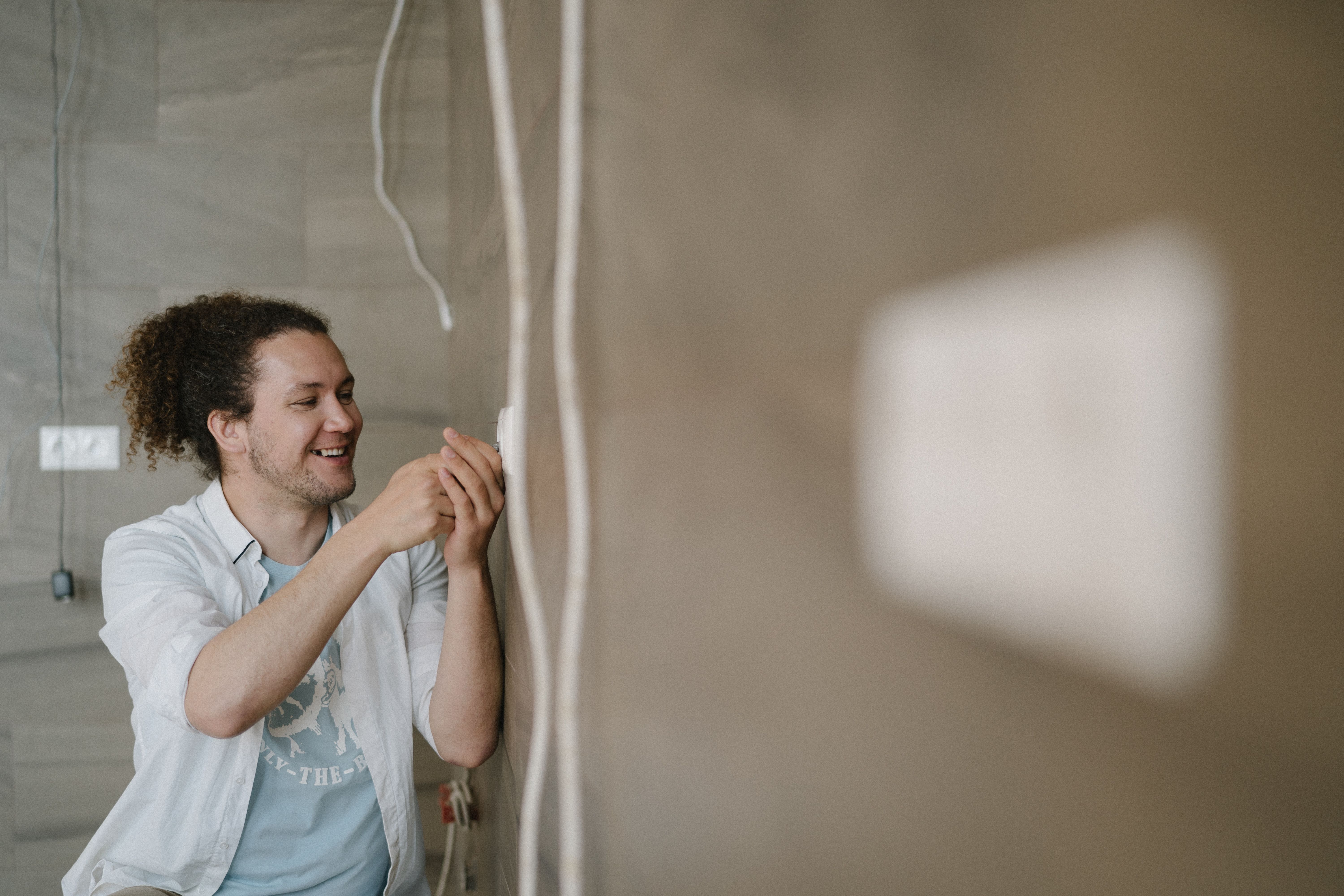 Smiling electrician working on an outlet representing a home service business