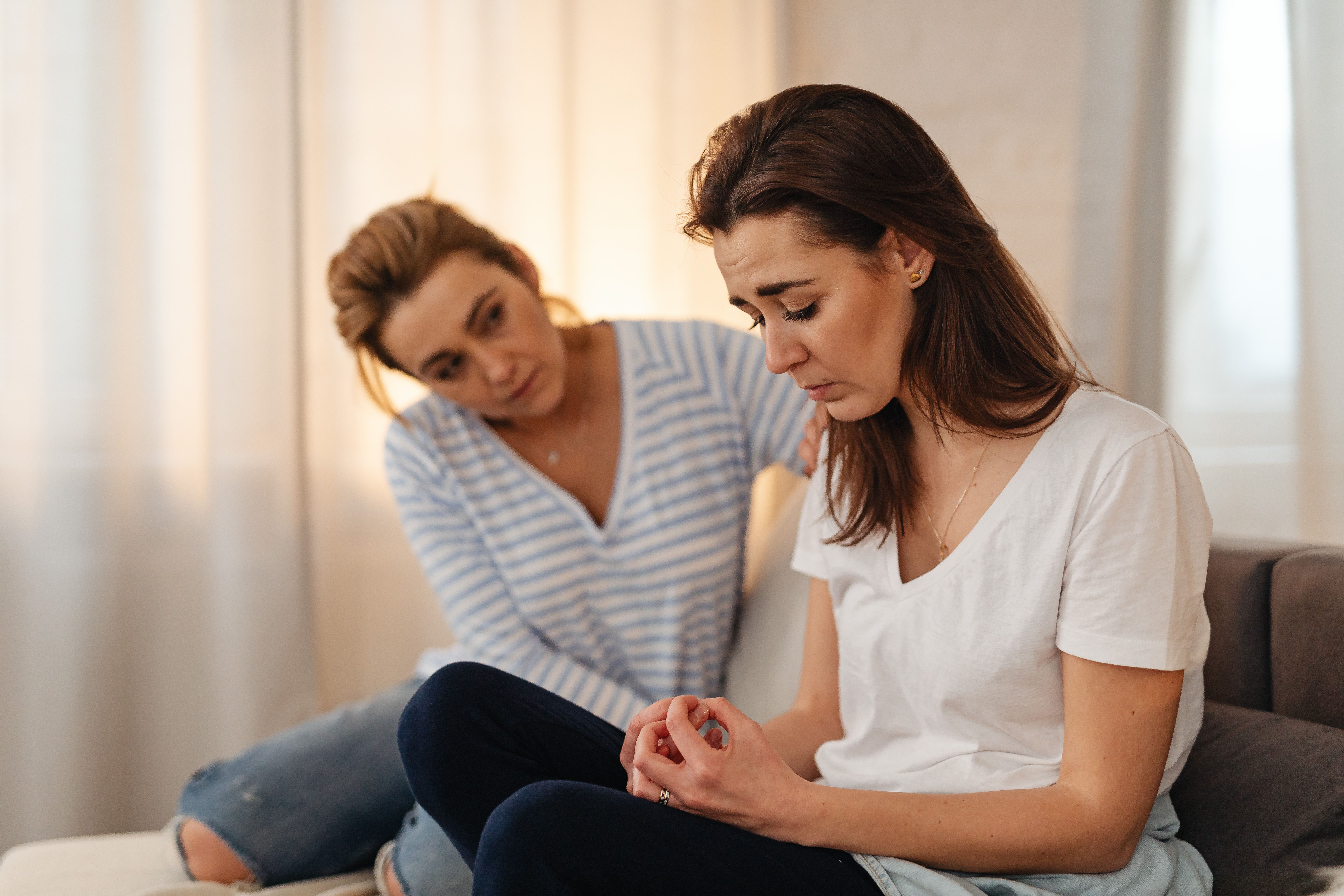 One woman listens closely and offers support as a friend talks on the couch.