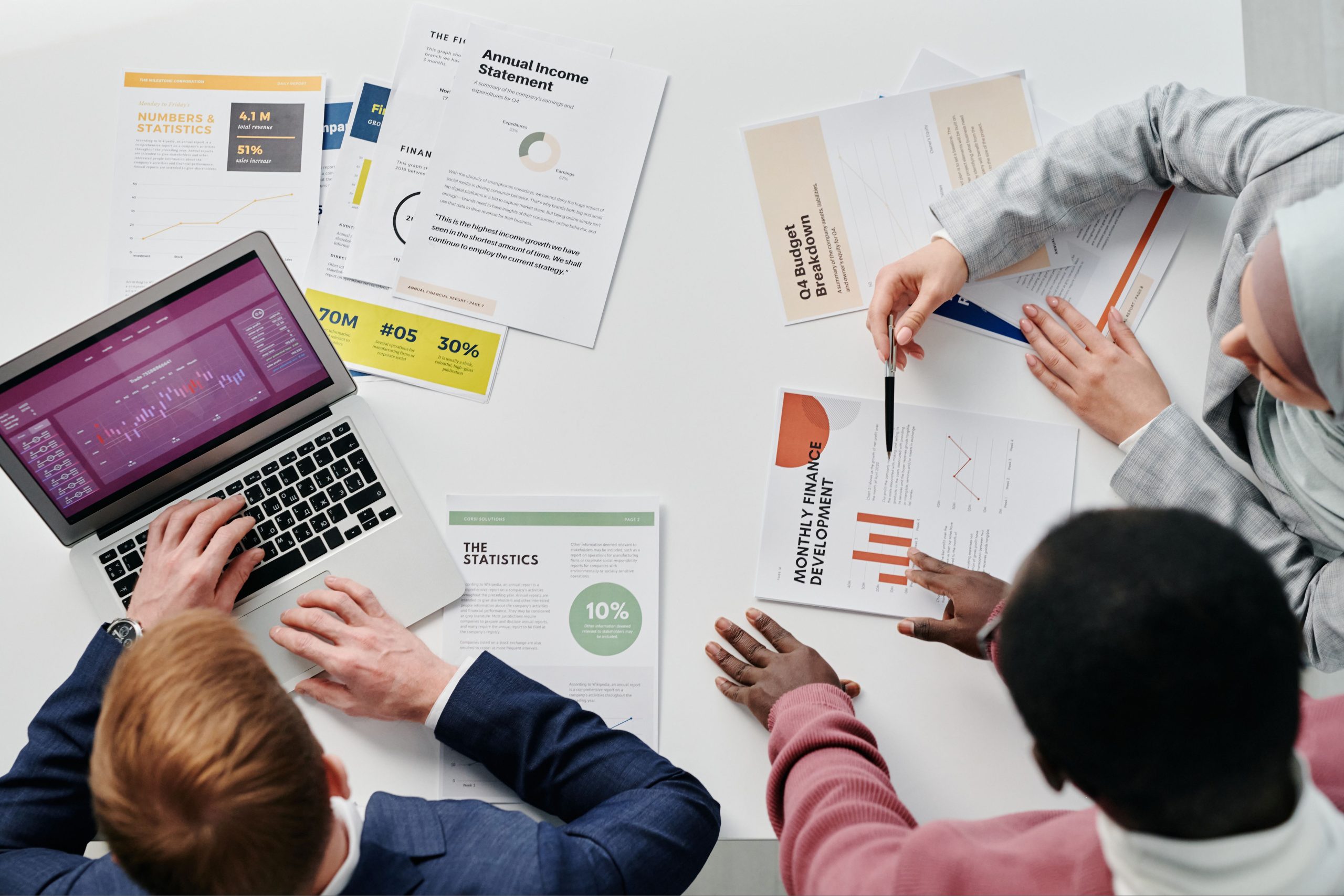 Colleagues openly reviewing financial reports and charts together around an office desk.