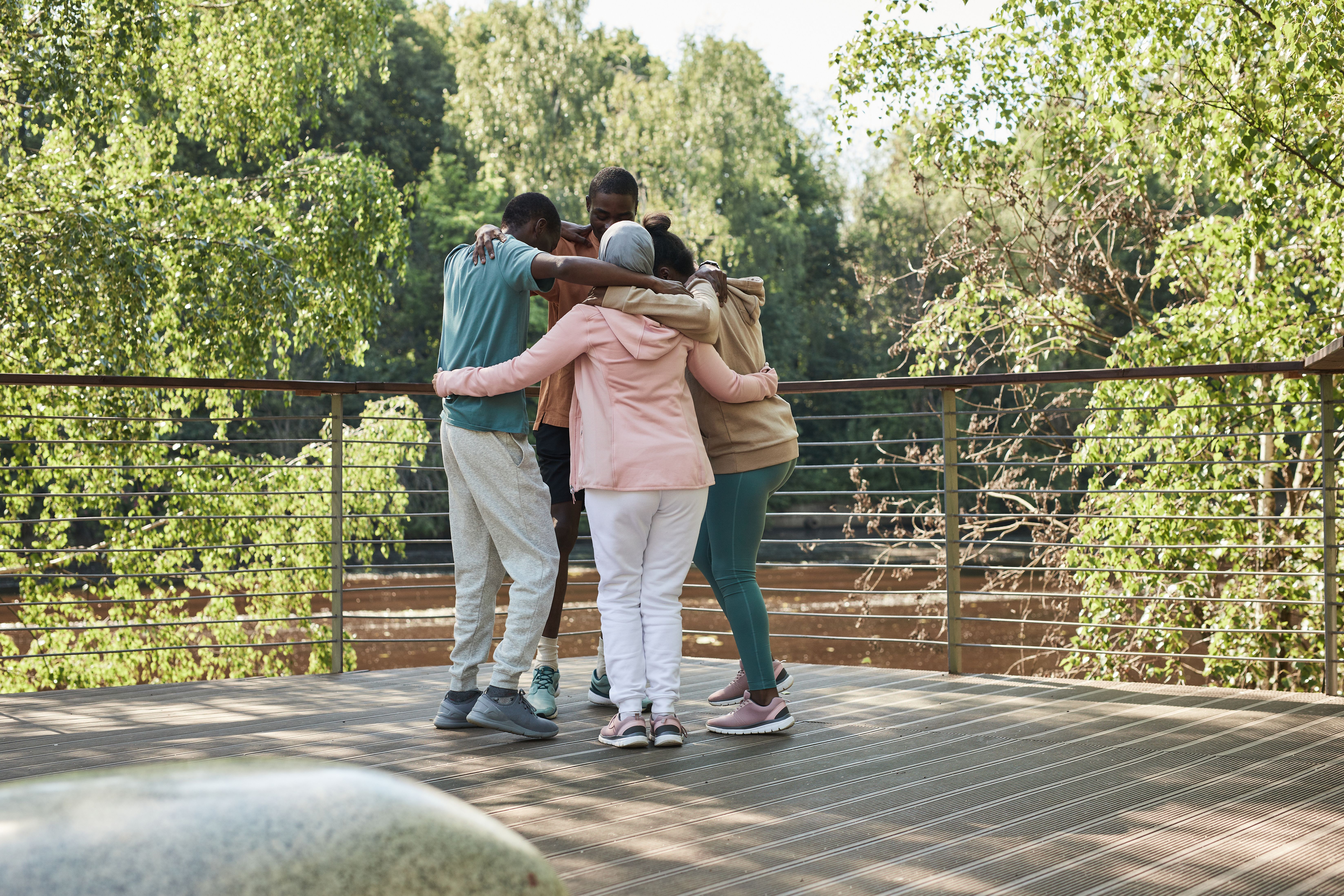 Friends embrace in a group hug outdoors, expressing warmth, belonging, and community connection.