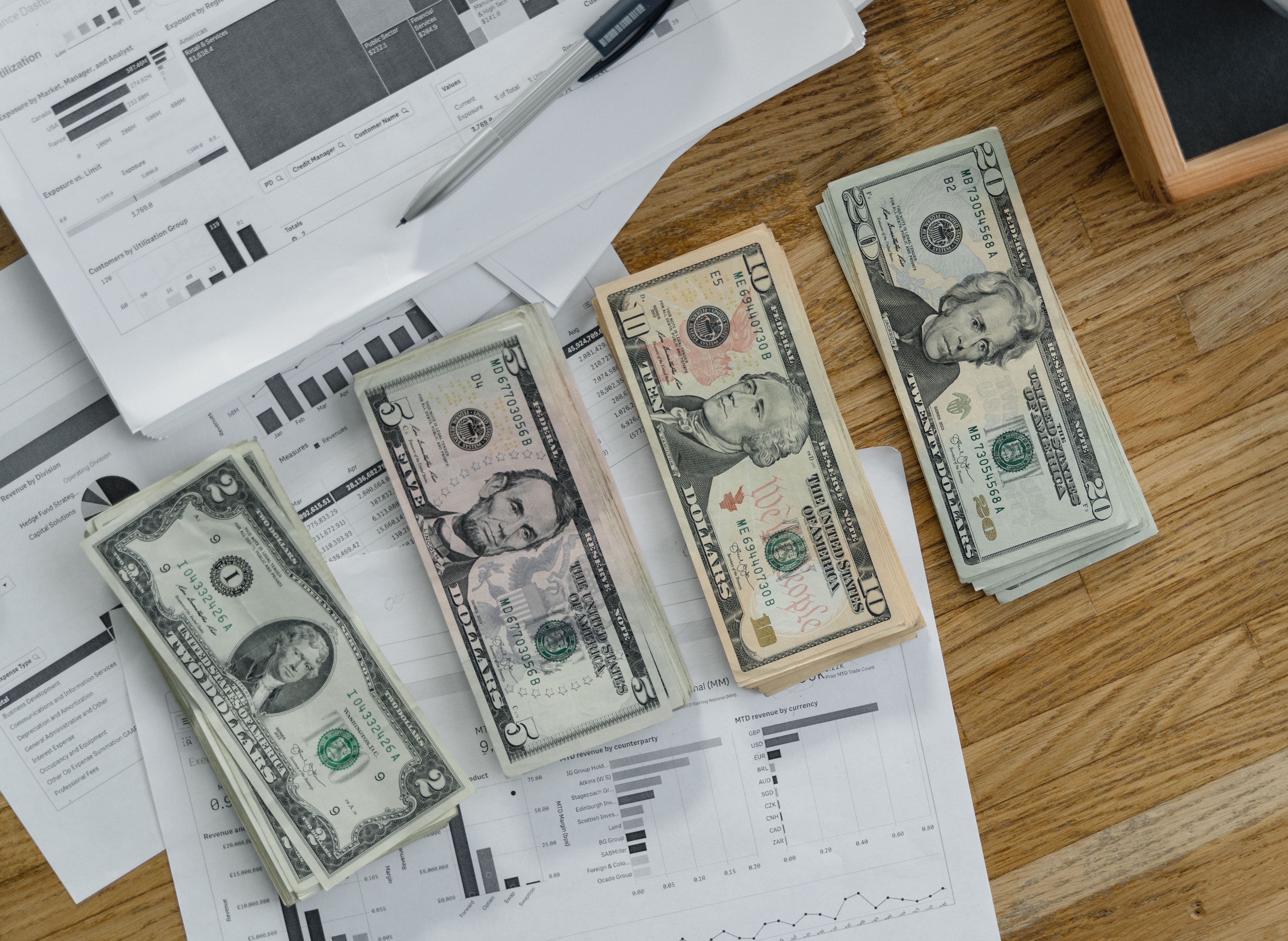 Stacks of US dollar banknotes over financial reports, representing capital raised for large-scale litigation