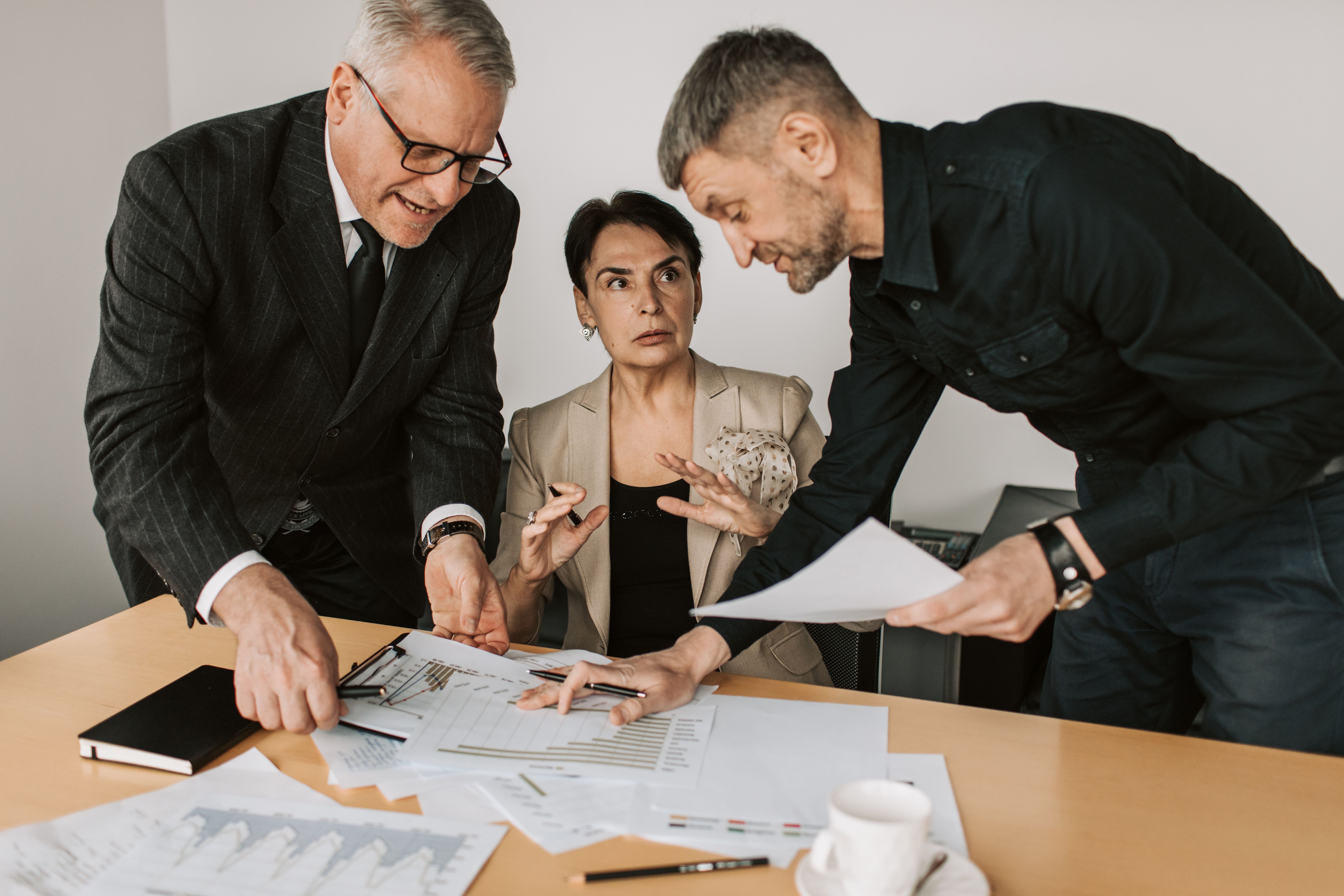 Three professionals analyzing documents and planning strategy at an office table, representing litigation investment teams