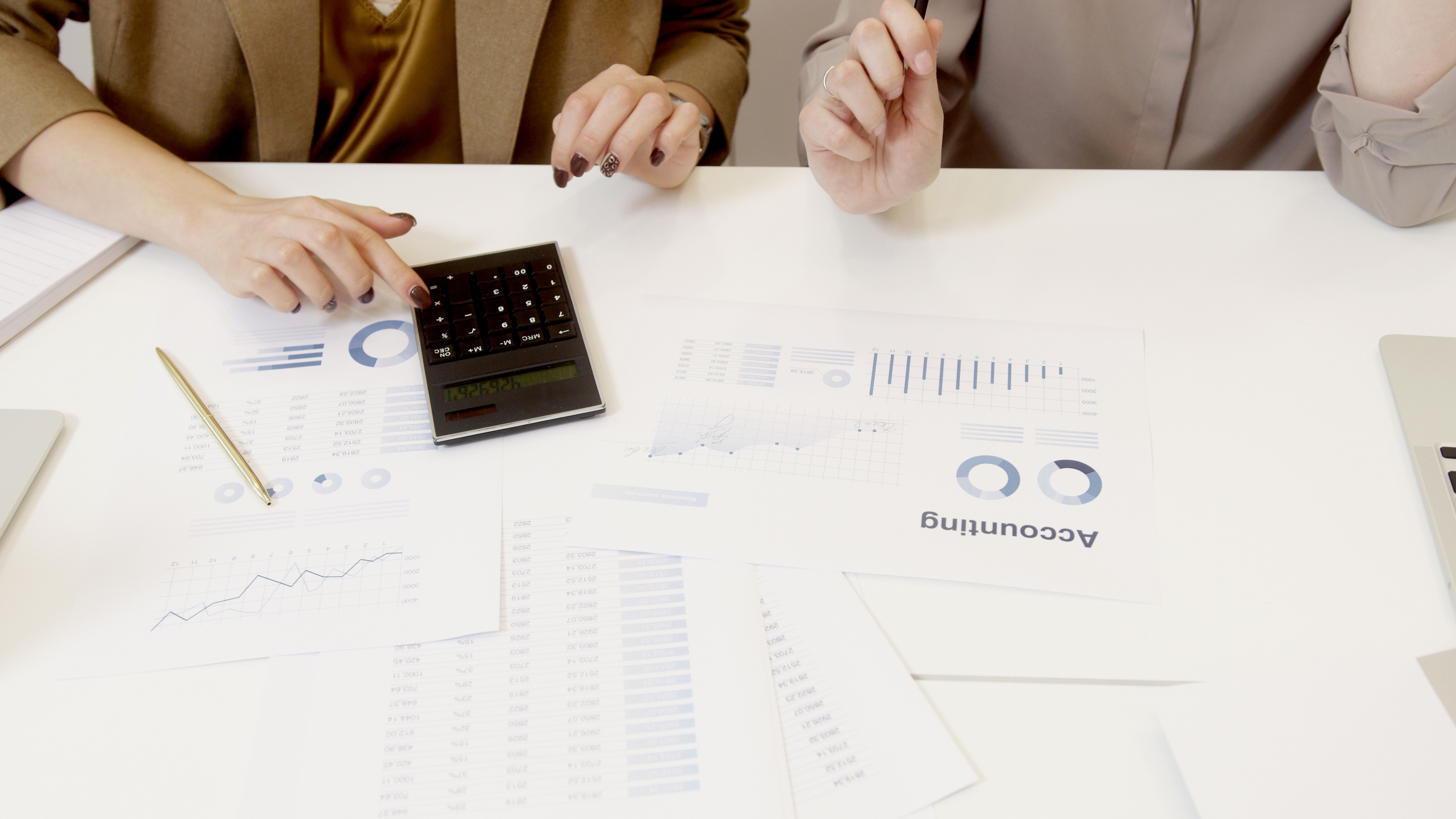 Two professionals checking financial documents and calculations with a calculator.